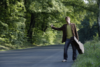 Young hitchhiking man with guitar - Alex Mares-Manton