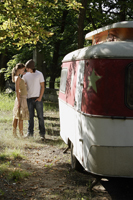 Young couple standing next to camper - Alex Mares-Manton