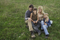 family sitting on grassy hill - Alex Mares-Manton