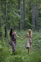 Two young women hand in hand in a forest - Alex Mares-Manton