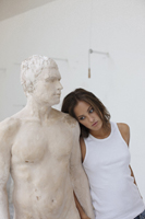 young woman leaning against sculpture of man - Dennison Bertrand