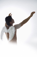 Man wearing angel wings, holding arms upward - Nugene Chiang