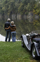 Senior couple standing next to pond, near antique car - Alex Mares-Manton