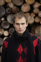 Portrait of young man against wall of stacked logs - Alex Mares-Manton