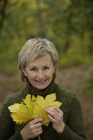 Senior woman holding autumn leaves - Alex Mares-Manton