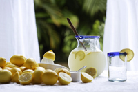 Pitcher of lemonade, glass, lemons on table in kitchen window - Alex Mares-Manton