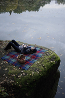 Young woman lying on blanket near lake - Alex Mares-Manton
