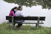 Young couple cuddling on lakeside bench - Alex Mares-Manton