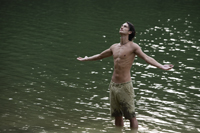 Young man standing in lake, arms open wide - Nugene Chiang