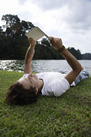 Young man reading on back, lakeside - Nugene Chiang