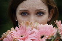 Close up of young woman smelling daisies - Alex Mares-Manton