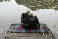 Senior couple sitting on blanket by lake - Alex Mares-Manton