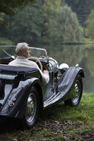 Senior man sitting in antique car near lake - Alex Mares-Manton