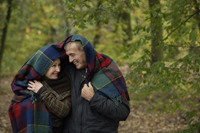 Senior couple embracing under blanket in woods - Alex Mares-Manton