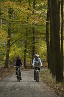 Young couple riding bikes through forest - Alex Mares-Manton