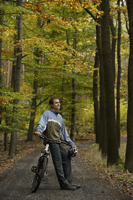 Young man taking rest from bike ride through forest - Alex Mares-Manton