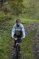 Senior man riding bike down trail - Alex Mares-Manton