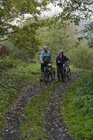 Senior couple walking bikes along trail - Alex Mares-Manton