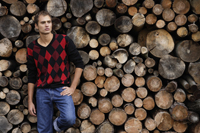 Young man leaning against wall of stacked logs - Alex Mares-Manton