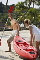 couple pulling kayak up beach - Alex Mares-Manton