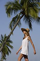 Woman walking under palm trees - Alex Mares-Manton