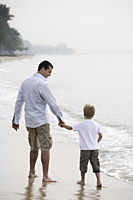 father and son walking on beach - Nugene Chiang