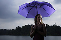 Woman holding purple umbrella in rain storm - Nugene Chiang