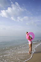 woman at beach with pink tube - Nugene Chiang