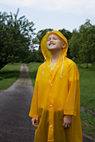young boy standing on road in rain coat - Nugene Chiang