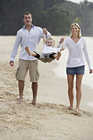 parents swinging kid on beach - Nugene Chiang