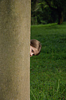 little girl peeking from behind tree trunk - Nugene Chiang