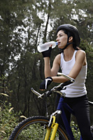 young woman riding bike, with water bottle - Nugene Chiang