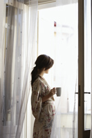 Young woman having morning coffee at open window - Alex Mares-Manton