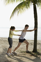 couple stretching stretching on beach - Nugene Chiang
