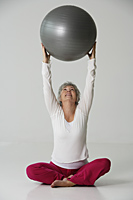Mature woman stretching with exercise ball. - Nugene Chiang