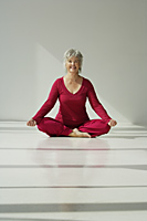 Mature woman smiling while doing yoga. - Nugene Chiang