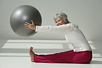 Mature woman stretching with exercise ball. - Nugene Chiang