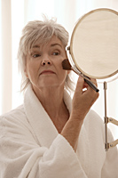 Older woman applying makeup. - Nugene Chiang