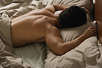 Back view of man sleeping in bed. - Nugene Chiang