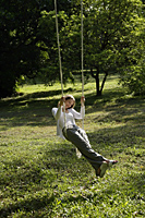 Woman swinging in a tree swing. - Nugene Chiang