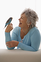 Older woman holding blue bird. - Nugene Chiang