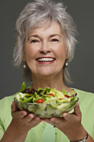 Mature woman holding salad. - Nugene Chiang