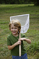 Little boy holding butterfly net, outside. - Nugene Chiang