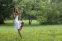 Woman in white dress sitting in tree swing. - Nugene Chiang