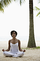 woman sitting on beach doing yoga, with eyes closed. - Alex Mares-Manton