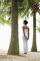 woman standing under coconut tree looking at the ocean. - Alex Mares-Manton