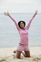 Woman on beach stretching her arms up and smiling - Alex Mares-Manton