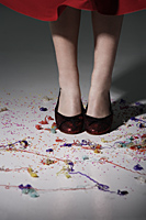 close up of woman wearing red shoes with confetti on the floor - Nugene Chiang