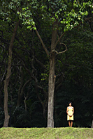 woman in yellow dress standing under trees. - Alex Mares-Manton