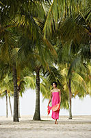Young woman walking on beach, under coconut trees. - Alex Mares-Manton